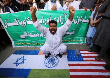 Άνδρας στην Πεσαβάρ του Πακιστάν κάθεται πάνω στις σημαίες της Ινδίας, του Ισραήλ και των ΗΠΑ κατά τη διάρκεια διαδήλωσης υποστήριξης των Παλαιστινίων (φωτ.: EPA/ ARSHAD ARBAB)