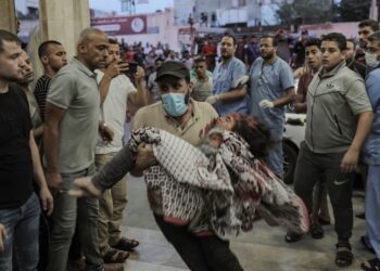 Άνδρας σπεύδει στο νοσοκομείο κρατώντας ένα τραυματισμένο παιδί μετά από ισραηλινό βομβαρδισμό στη Γάζα (φωτ.: EPA/Haitham Imad)