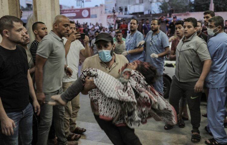 Άνδρας σπεύδει στο νοσοκομείο κρατώντας ένα τραυματισμένο παιδί μετά από ισραηλινό βομβαρδισμό στη Γάζα (φωτ.: EPA/Haitham Imad)