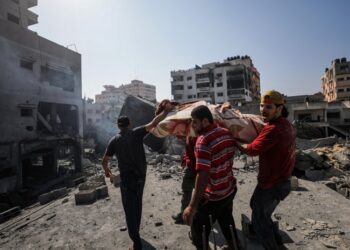 Παλαιστίνιοι μεταφέρουν μια σορό ανάμεσα στα ερείπια κτηρίων μετά από ισραηλινό βομβαρδισμό σε συνοικία της Γάζας (φωτ.: EPA/Mohammed Saber)