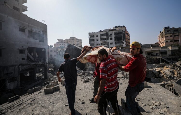 Παλαιστίνιοι μεταφέρουν μια σορό ανάμεσα στα ερείπια κτηρίων μετά από ισραηλινό βομβαρδισμό σε συνοικία της Γάζας (φωτ.: EPA/Mohammed Saber)