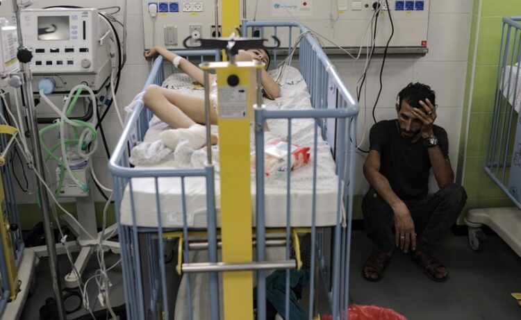 Παλαιστίνιος κάθεται δίπλα στο τραυματισμένο παιδί του, το οποίο νοσηλεύεται στη ΜΕΘ νοσοκομείου της Γάζας (φωτ.: EPA/Haitham Imad)