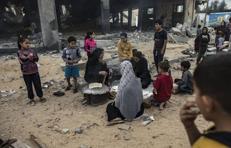 Εκτοπισμένοι Παλαιστίνιοι μπροστά από τα ερείπια βομβαρδισμένου κτηρίου (φωτ.: EPA / Haitham Imad)