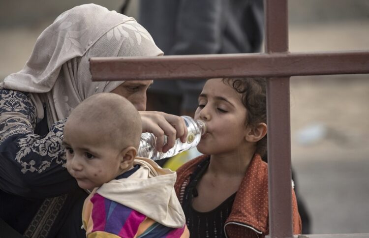 Παλαιστίνια δίνει νερό στα παιδιά της ενώ εγκαταλείπουν τα βόρεια τμήματα της Γάζας (φωτ.: EPA/Haitham Imad)