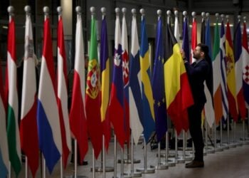 Υπάλληλος τακτοποιεί τις ευρωπαϊκές σημαίες στη διάρκεια του Ευρωπαϊκού Συμβουλίου στις Βρυξέλλες (φωτ.: EPA/Olivier Matthys)