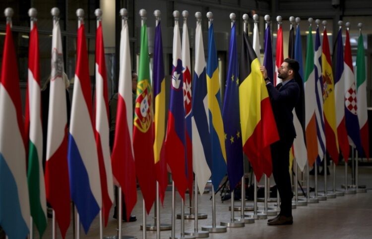 Υπάλληλος τακτοποιεί τις ευρωπαϊκές σημαίες στη διάρκεια του Ευρωπαϊκού Συμβουλίου στις Βρυξέλλες (φωτ.: EPA/Olivier Matthys)