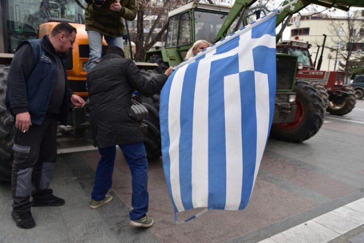 Αγρότες κρατάνε την ελληνική σημαία κατά τη διάρκεια της συμμετοχής τους σε μπλόκο στην κεντρική πλατεία Λάρισας (φωτ.: ΑΠΕ-ΜΠΕ/Αποστόλης Ντόμαλης)