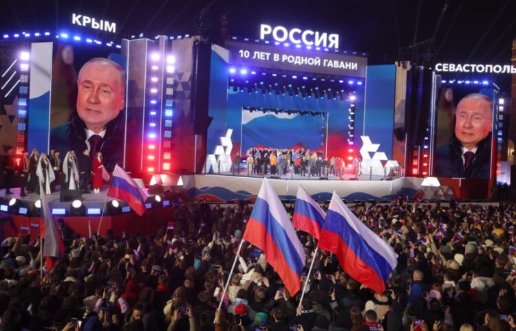 Ο Ρώσος πρόεδρος Βλαντίμιρ Πούτιν διακρίνεται σε γιγαντοοθόνες, στη διάρκεια εορτασμών για τη δέκατη επέτειο προσάρτησης της Κριμαίας στη Ρωσία, μία ημέρα μετά τη λήξη των εκλογών στη χώρα και την επανεκλογή του, η οποία αμφισβητείται ανοιχτά από τη Δύση (φωτ.: EPA/Sergei Ilnitsky)