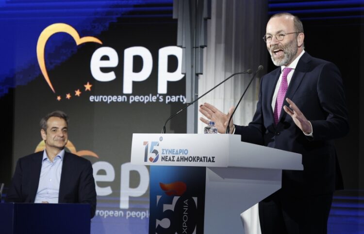 Ο Μάνφρεντ Βέμπερ στο βήμα του συνεδρίου της ΝΔ και αριστερά ο Κυριάκος Μητσοτάκης (φωτ.: EUROKINISSI/Γιώργος Κονταρίνης)