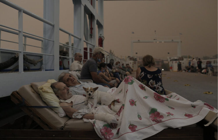 Ο Γεώργιος Λιάκος 89 ετών και η σύζυγός του Παρισσώ Λιάκου 87 ετών κάτοικοι του χωριού Πευκί, περιμένουν μαζί με το σκυλάκι τους Bella, στο κατάστρωμα φέρι μποτ το οποίο βρίσκεται σε αναμονή  στην παραλία του χωριού για να συνδράμει στην εκκένωση του χωριού κατά τη διάρκεια δασικής πυρκαγιάς στην Βόρεια Εύβοια, Κυριακή 08 Αυγούστου 2021 (φωτ.: ΑΠΕ-ΜΠΕ/ Κώστας Τσιρώνης)