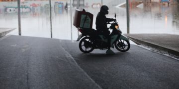 Διανομέας κάνει αναστροφή με το μηχανάκι τους μπροστά από τη γέφυρα όπου ένα λεωφορείο εγκλωβίστηκε και «βούλιαξε» στο νερό που συγκεντρώθηκε, στο ύψος του Δέλτα Φαλήρου από την κακοκαιρία «Μπάλλος» (φωτ.: 
ΑΠΕ-ΜΠΕ/ΓΙΩΡΓΟΣ ΒΙΤΣΑΡΑΣ)