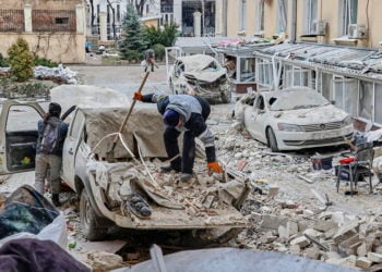 Άνθρωποι καθαρίζουν τα συντρίμμια στο Χάρκιβ (φωτ.: EPA/ Sergey Kozlov)