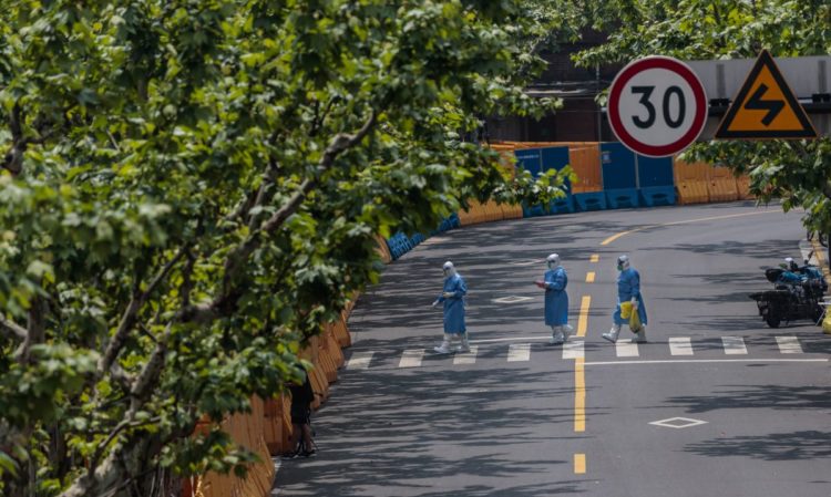 Άνθρωποι με προστατευτικό εξοπλισμό προχωρούν προς την είσοδο περιοχής που βρίσκεται σε καραντίνα, λόγω της Covid-19 (φωτ.: EPA/ Alex Plavevski)