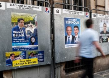 Ένας άνδρας περπατά μπροστά από αφίσες υποψηφίων των βουλευτικών εκλογών, σε περιοχή του Παρισιού (φωτ.: ΕΡΑ/ Mohammed Barda)