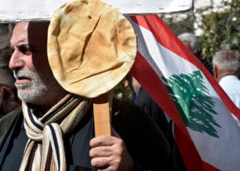 Διαδηλωτής έχει καρφώσει στο πλακάτ λιβανέζικο ψωμί (φωτ.: EPA / Wael Hamzeh)