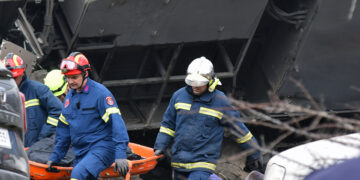 Πυροσβέστες μεταφέρουν σορό από τα συντρίμμια του τρένου (φωτ.: ΑΠΕ-ΜΠΕ / Αποστόλης Ντόμαλης)