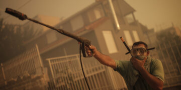 Πολίτης φορώντας μάσκα καταδύσεων και χρησιμοποιώντας πιεστικό ρίχνει νερό σε σπίτι κατά τη διάρκεια της πυρκαγιάς στο Λαγονήσι (φωτ.: ΑΠΕ-ΜΠΕ / Κώστας Τσιρώνης)