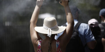 Τουρίστρια περπατάει δίπλα από καφετέρια που ψεκάζει νερό, στο κέντρο της Αθήνας (φωτ.: ΑΠΕ-ΜΠΕ / Γιάννης Κολεσίδης)