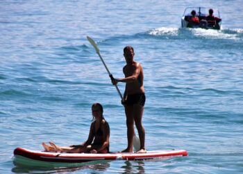 Λουόμενοι απολαμβάνουν τη θάλασσα σε σανίδα SUP (φωτ. αρχείου: pixabay/pasja1000)