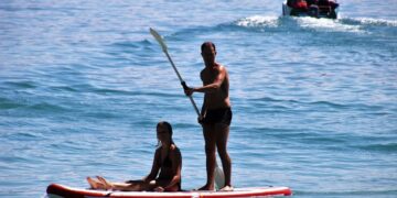 Λουόμενοι απολαμβάνουν τη θάλασσα σε σανίδα SUP (φωτ. αρχείου: pixabay/pasja1000)
