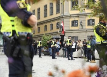 Σουηδοί αστυνομικοί φρουρούν ομάδα μουσουλμάνων που διαμαρτύρεται για το κάψιμο του Κορανίου σε πλατεία της Στοκχόλμης (φωτ.: EPA/Oscar Olsson)
