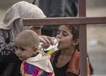 Παλαιστίνια δίνει νερό στα παιδιά της ενώ εγκαταλείπουν τα βόρεια τμήματα της Γάζας (φωτ.: EPA/Haitham Imad)