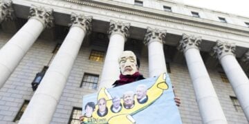 Διαδηλωτής κρατά πανό με φωτογραφίες, από αριστερά, της Ζισλέν Μάξγουελ, του Τζέφρι Επστάιν, του Μπιλ Γκέιτς, του Ντόναλντ Τραμπ και του Μπιλ Κλίντον, έξω από το Ομοσπονδιακό Δικαστήριο της Νέας Υόρκης, όταν διεξαγόταν η δίκη της Ζισλέν Μάξγουελ, τον Νοέμβριο του 2021 (φωτ. αρχείου: EPA/Justin Lane)