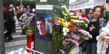 Φωτογραφία του Ιάσονα Λαλαούνη και λουλούδια σε κολόνα έξω από την είσοδο της Βουλής επί της Β. Σοφίας (φωτ.: EUROKINISSI / Γιάννης Παναγόπουλος)