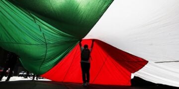 Άνδρας κάτω από μια τεράστια παλαιστινιακή σημαία (φωτ.: EPA / Elvis Gonzalez)