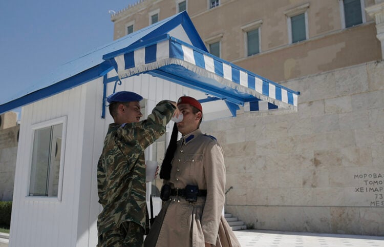 Μέλος της Προεδρικής Φρουράς προσφέρει νερό σε Εύζωνα που εκτελεί την υπηρεσία του στο Μνημείο του Άγνωστου Στρατιώτη (φωτ.: ΑΠΕ-ΜΠΕ / Κώστας Τσιρώνης)