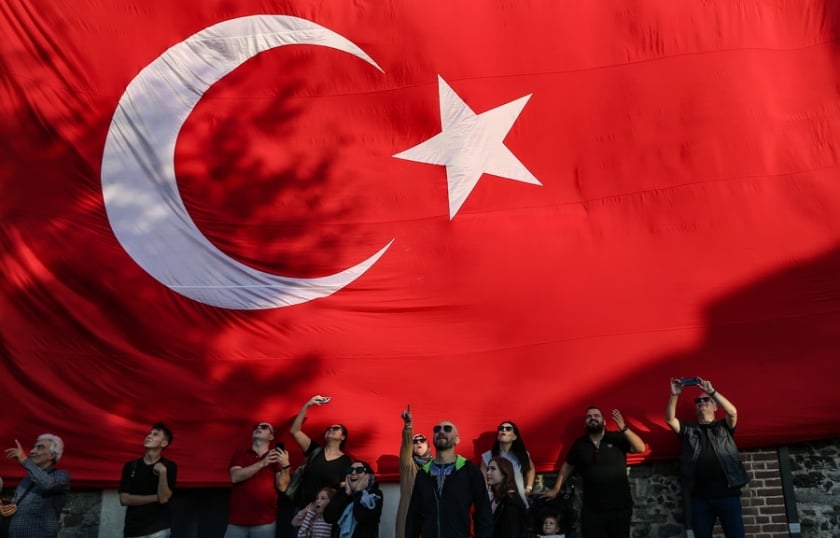 Πολίτες στέκονται μπροστά από μια γιγάντια τουρκική σημαία στη διάρκεια εθνικών εορτασμών στην Κωνσταντινούπολη (φωτ.: EPA / Erdem Sahin)