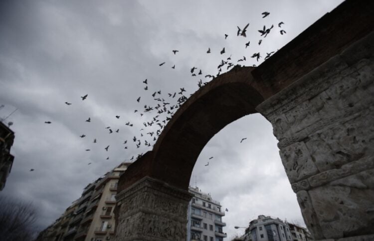 Περιστέρια πετούν γύρω από το μνημείο της Καμάρας σε μια συννεφιασμένη Θεσσαλονίκη (φωτ.: ΑΠΕ-ΜΠΕ / Δημήτρης Τοσίδης)