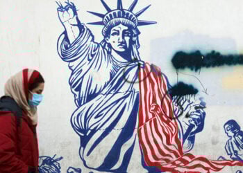 Μια Ιρανή περνά δίπλα από αντι-αμερικανική τοιχογραφία έξω από το πρώην κτήριο της πρεσβείας των ΗΠΑ στην Τεχεράνη, μία ημέρα μετά την ορκωμοσία του Ντόναλντ Τραμπ ως 47ου προέδρου των ΗΠΑ. Τεχεράνη, 21 Ιανουαρίου 2025. (φωτ.: EPA / Abedin Taherkenareh)