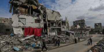 Παλαιστίνιοι περπατούν μπροστά από κατεστραμμένα σπίτια στη Γάζα (φωτ.: EPA / Mohammed Saber)