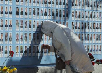 Ουκρανή στο Κίεβο γέρνει θλιμμένη πάνω σε τοίχο με τις φωτογραφίες πεσόντων στον πόλεμο με τη Ρωσία (φωτ.: . EPA/Sergey Dolzhenko)
