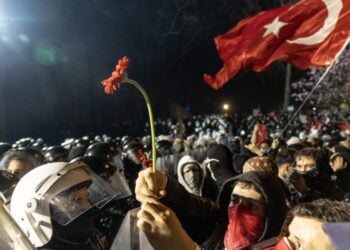 Διαδηλωτής στην πλατεία Ταξίμ κρατά ένα λουλούδι μπροστά από τους αστυνομικούς που φρουρούν το δημαρχείο της Κωνσταντινούπολης (φωτ.: EPA/Erdem Sahin)