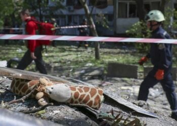 Ουκρανοί διασώστες προσπερνούν ερείπια στα οποία διακρίνεται ένα παιδικό κουκλάκι μετά την κατάρρευση πολυκατοικίας από ρωσικό πύραυλο στη Ζαπορίζια (φωτ.: EPA/Oleg Movchaniuk)