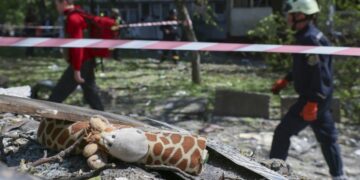Ουκρανοί διασώστες προσπερνούν ερείπια στα οποία διακρίνεται ένα παιδικό κουκλάκι μετά την κατάρρευση πολυκατοικίας από ρωσικό πύραυλο στη Ζαπορίζια (φωτ.: EPA/Oleg Movchaniuk)