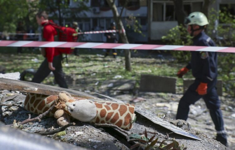 Ουκρανοί διασώστες προσπερνούν ερείπια στα οποία διακρίνεται ένα παιδικό κουκλάκι μετά την κατάρρευση πολυκατοικίας από ρωσικό πύραυλο στη Ζαπορίζια (φωτ.: EPA/Oleg Movchaniuk)