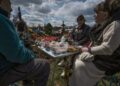 Οικογένεια Ουκρανών έχει στήσει ένα πρόχειρο τραπέζι με φαγητό δίπλα στον τάφο συγγενικού προσώπου, για το ταφικό έθιμο «Ημέρα Χαράς», ή «Προβόντι», παρόμοιο με αυτό των Ποντίων. Μία εβδομάδα μετά το Πάσχα, οι συγγενείς των νεκρών φέρνουν στο νεκροταφείο φαγητό, λουλούδια και προσωπικά αντικείμενα των νεκρών, προκειμένου να περάσουν την ημέρα μαζί (φωτ.: . EPA/Maria Senovilla)