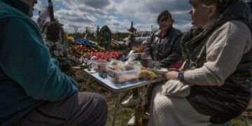 Οικογένεια Ουκρανών έχει στήσει ένα πρόχειρο τραπέζι με φαγητό δίπλα στον τάφο συγγενικού προσώπου, για το ταφικό έθιμο «Ημέρα Χαράς», ή «Προβόντι», παρόμοιο με αυτό των Ποντίων. Μία εβδομάδα μετά το Πάσχα, οι συγγενείς των νεκρών φέρνουν στο νεκροταφείο φαγητό, λουλούδια και προσωπικά αντικείμενα των νεκρών, προκειμένου να περάσουν την ημέρα μαζί (φωτ.: . EPA/Maria Senovilla)