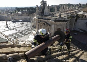 Εργάτες τοποθετούν την καμινάδα για τον καπνό που θα σημάνει την εκλογή του νέου πάπα στη στέγη της Καπέλα Σιξτίνα, ενώ στο βάθος διακρίνεται η πλατεία του Αγίου Πέτρου (φωτ.: Γραφείο Τύπου Βατικανού)