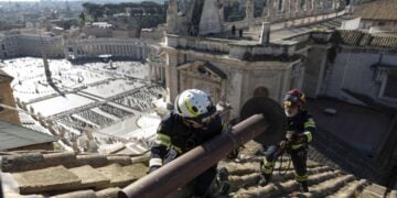 Εργάτες τοποθετούν την καμινάδα για τον καπνό που θα σημάνει την εκλογή του νέου πάπα στη στέγη της Καπέλα Σιξτίνα, ενώ στο βάθος διακρίνεται η πλατεία του Αγίου Πέτρου (φωτ.: Γραφείο Τύπου Βατικανού)