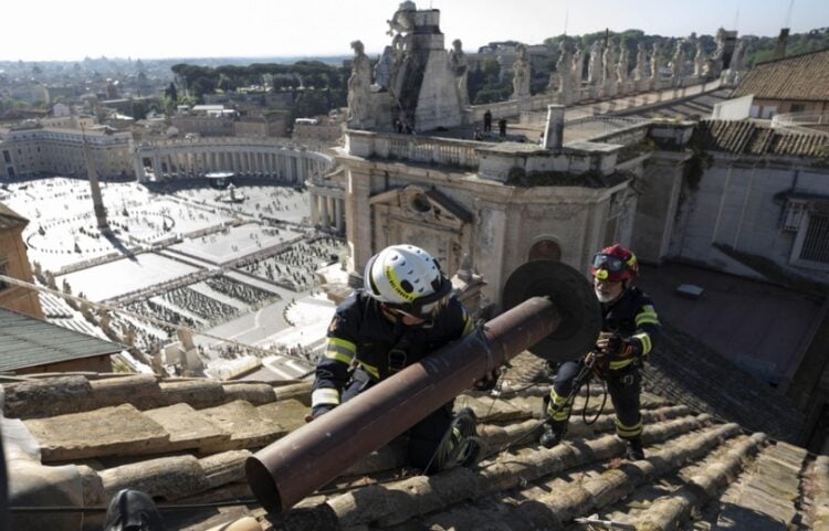 Εργάτες τοποθετούν την καμινάδα για τον καπνό που θα σημάνει την εκλογή του νέου πάπα στη στέγη της Καπέλα Σιξτίνα, ενώ στο βάθος διακρίνεται η πλατεία του Αγίου Πέτρου (φωτ.: Γραφείο Τύπου Βατικανού)