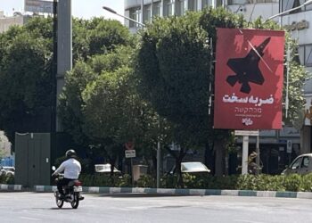 Ιρανός στην Τεχεράνη προσπερνά αφίσα η οποία αναγράφει «Σκληρή απάντηση» απεικονίζοντας ένα βομβαρδιστικό (φωτ.: EPA/Abedin Taherkenareh)