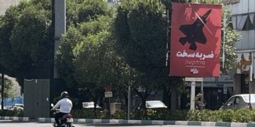 Ιρανός στην Τεχεράνη προσπερνά αφίσα η οποία αναγράφει «Σκληρή απάντηση» απεικονίζοντας ένα βομβαρδιστικό (φωτ.: EPA/Abedin Taherkenareh)
