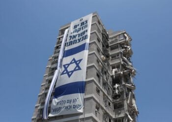Πανό με την ισραηλινή σημαία στο κτήριο που έπεσε ιρανικός βαλιστικός πύραυλος στις 15 Ιουνίου. Στο πανό γράφει «Το Μπατ Γιάμ είναι δυνατό. Το Ισραήλ κερδίζει!» (πηγή:
EPA/Abir Sultan)