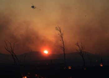 Πυροσβεστικό ελικόπτερο επιχειρεί στιγμές πριν από τη δύση του ηλίου στη Δροσοπηγή (φωτ.: EUROKINISSI/Τατιάνα Μπόλαρη)