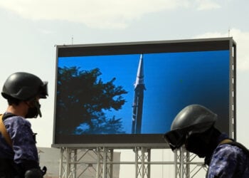 Αντάρτες Χούθι με φόντο μια γιγαντοαφίσα που δείχνει έναν πύραυλο, στην πρωτεύουσα της Υεμένης, Σαναά (φωτ.: EPA / Yahya Arhab)