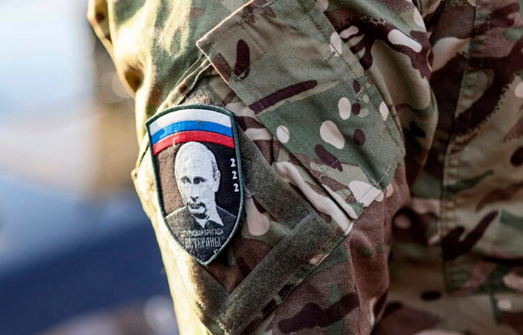 Στρατιώτης με διακριτικό που φέρει την εικόνα του Βλαντίμιρ Πούτιν και την ένδειξη «Assault Brigade Veterans» παρευρίσκεται σε εκδήλωση αποστολής βοήθειας προς τις εμπόλεμες ζώνες στην Ουκρανία (φωτ.: EPA / Sergei Ilnitsky)